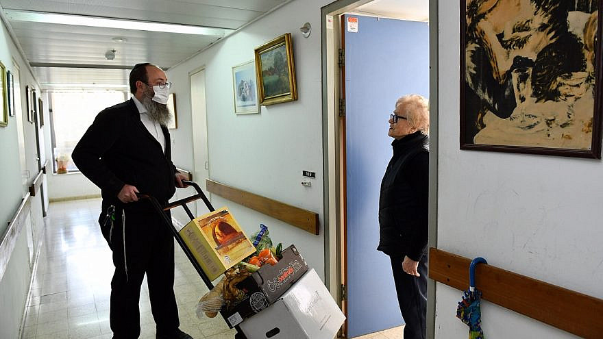 Rabbi Menachem Traxler, director of volunteering for Colel Chabad, makes his way up the stairs with a handtruck to deliver food to the elderly and homebound in Israel. Credit: Mendy Hechtman.