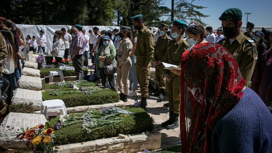 People stand still next to the graves of fallen soldiers at the Mount Herzl cemetery in Jerusalem as a two-minute siren sounds, marking Israel's Memorial Day, April 14, 2021. Photo by Olivier Fitoussi/Flash90.