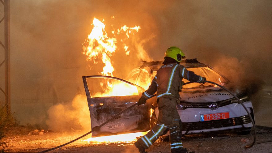 An Israeli police car burns in Lod, where Arab rioters have torched synagogues, shops and vehicles. May 12, 2021. Photo by Yossi Aloni/Flash90.