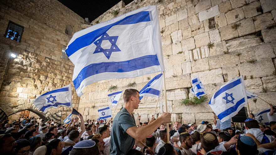 Israelis wave flags at the Western Wall in Jerusalem's Old City on the eve of Jerusalem Day, May 9, 2021. Photo by Yonatan Sindel/Flash90.