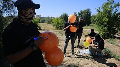 Masked supporters of Palestinian Islamic Jihad prepare incendiary balloons east of Gaza City to launch across the border fence towards Israel on June 15, 2021. Photo by Atia Mohammed/Flash90.