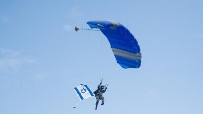 An Israeli paratrooper holding flying the flag of Israel while parachuting over Slovenia as part of commemoration of Jewish World War II paratroopers. Credit: IDF.