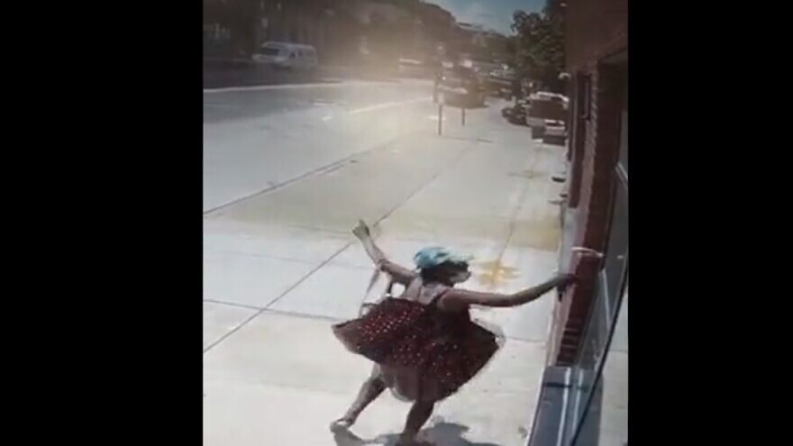 Surveillance camera footage caught an African-American woman in the act of using a hammer to break a glass window of a Jewish school in Brooklyn, N.Y., July 15, 2021. Source: Screenshot.