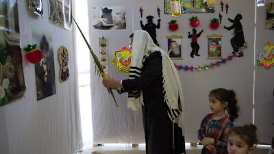 A man waves a lulav in a sukkah in Beitar Illit on Oct. 7, 2020. Photo by Nati Shohat/Flash90.