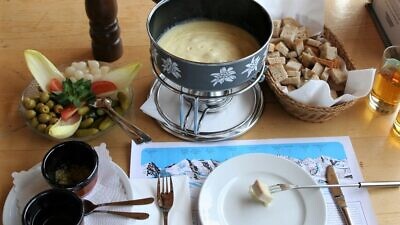 A full cheese fondue set in Switzerland. Apart from pieces of bread to dip into the melted cheese, it comes with side servings of kirsch, raw garlic, olives, pickled gherkins and baby onions. Credit: Wikimedia Commons.