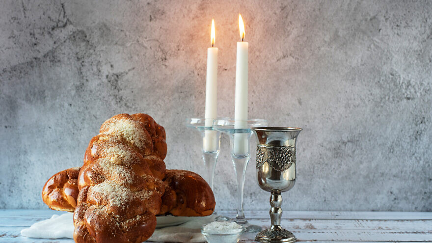 Challah bread, shabbat wine and candles on wooden table. Credit: BigNazik/Shutterstock.