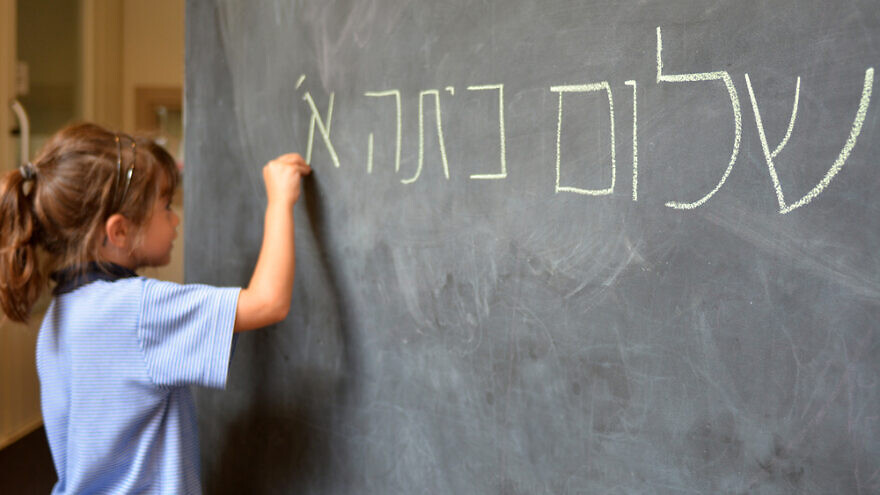 A student writes “Hello, First Grade” greetings in Hebrew. Credit:  ChameleonsEye/Shutterstock.