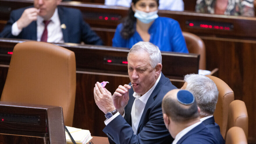 Israeli Defense Minister Benny Gantz sucks on a lollipop while talking to Prime Minister Naftali Bennett and Foreign Minister Yair Lapid during a plenum session and a vote on the state budget at the Knesset in Jerusalem, Nov. 3, 2021. Photo by Olivier Fitoussi/Flash90.