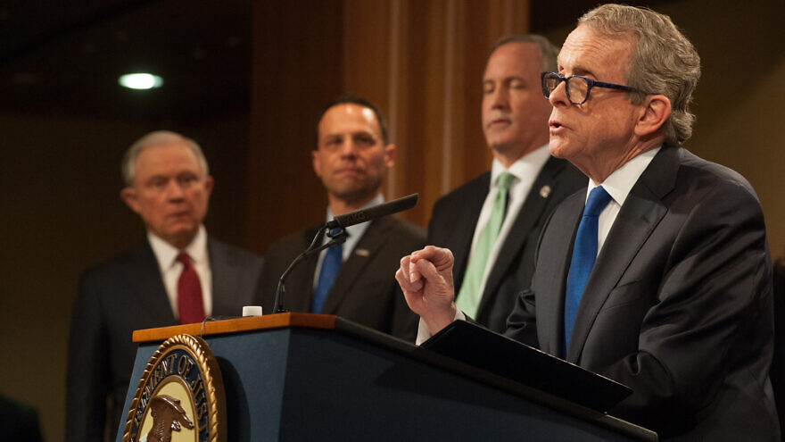 Mike DeWine (at podium) as Ohio attorney general before he became governor in January 2019, at the U.S. Department of Justice with (from left) U.S. Attorney General Jeff Sessions, Pennsylvania Attorney General Josh Shapiro and Texas Attorney General Ken Paxton on Feb. 27, 2018. Credit: U.S. Department of Justice via Wikimedia Commons.