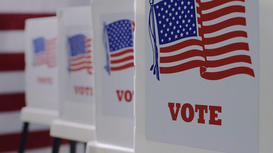 Straight on row of voting booths at polling station during American election. Credit: Shutterstock/vesperstock.