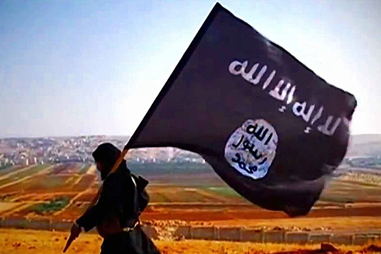 A terrorist carries the Islamic State's flag overlooking Dabiq in Syria, in 2013. Source: Wikimedia Commons.