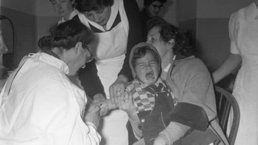 A child afflicted with polio is treated at the Tzrifin army base in Israel, during a visit by Hadassah representatives and Israel Police officers, 1954. Credit: The Eddie Hirschbein Collection.