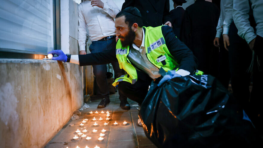 A member of the ZAKA organization lights candles at the scene of a terror attack in Bnei Brak that left five dead, March 29, 2022. Photo by Olivier Fitoussi/Flash90.