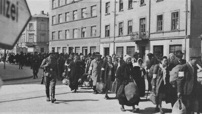 Jewish men, women and children march with bundles down the main thoroughfare in Krakow, Poland, during the liquidation of the Krakow Ghetto by Nazi German soldiers, March 1943. Credit: United States Holocaust Memorial Museum, courtesy of Instytut Pamieci Narodowejvia via Wikimedia Commons.