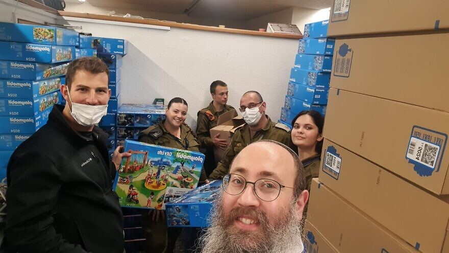 Rabbi Menachem Traxler, director of volunteering for Colel Chabad, with members of the Israel Defense Forces organizing gifts for children, including Ukrainian refugees. Credit: Pantry Packers.