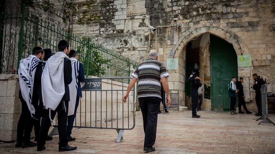 Jewish men watch an entrance to the Temple Mount in Jerusalem's Old City as police officers stand guard, April 19, 2022. Credit: Yonatan Sindel/Flash90.