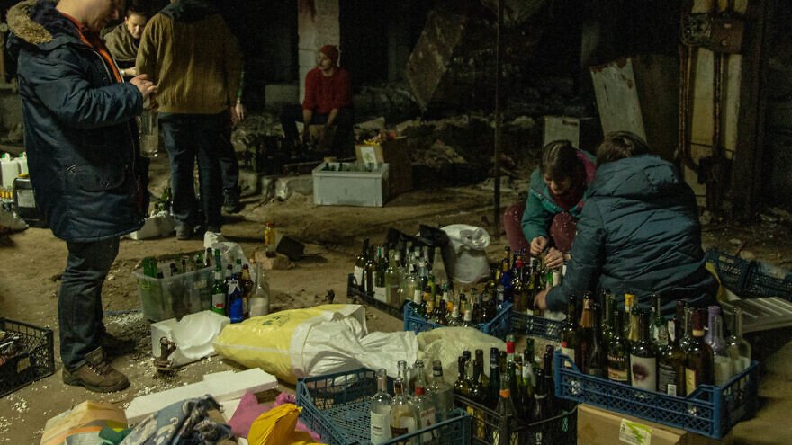 A group of civilians in Kyiv, Ukraine, gather in a city basement to make Molotov cocktails to be used against invading Russian troops, Feb. 26, 2022. Credit: Yan Boechat/VOA via Wikimedia Commons.