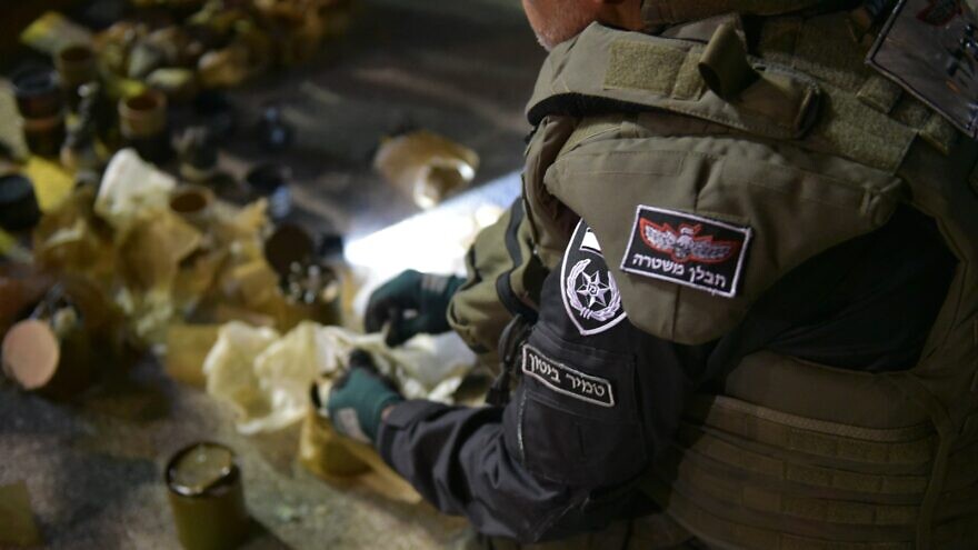 An Israel Police bomb disposal expert examines a shipment of grenades intercepted on the Israel-Lebanon border, on April 25, 2022. Credit: Israel Police.