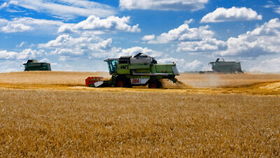 Harvesters work in the wheat field in Ukraine. Credit: zmeypetrov/Shutterstock.