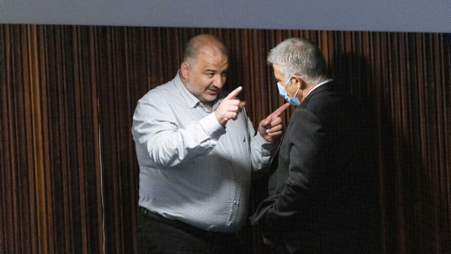 Then-Israeli Foreign Minister Yair Lapid (right) and Ra'am Party head Mansour Abbas talk during a plenum session in the Knesset, on July 1, 2021. Photo by Yonatan Sindel/Flash90.