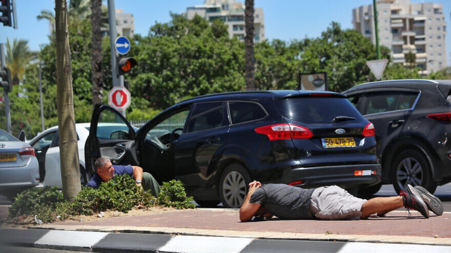 Israelis take cover as a siren warns of incoming rockets from Gaza, in Ashkelon, on May 19, 2021. Photo by Edi Israel/Flash90.