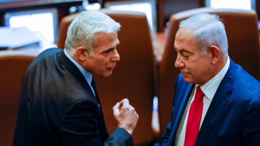 Opposition leader Yair Lapid, then the foreign minister, walks past Prime Minister Benjamin Netanyahu, at the time the leader of the opposition, at the Knesset in Jerusalem, Nov. 8, 2021. Photo by Olivier Fitoussi/Flash90.
