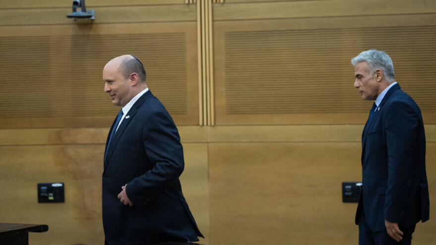 Israeli Prime Minister Naftali Bennett (left) and Foreign Minister Yair Lapid approach the podium ahead of a press conference at the Knesset to announce its disbanding, June 20, 2022. Photo by Yonatan Sindel/Flash90.