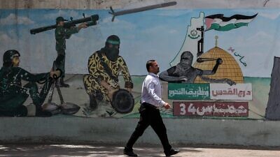 A Palestinian man walks next to graffiti depicting Hamas fighters firing rockets, in Khan Younis town in the southern Gaza Strip, on May 30, 2022. Photo by Abed Rahim Khatib/Flash90.