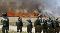Israeli soldiers walk amidst smoke from a fire in a wheat field near the Kibbutz of Nahal Oz, along the border with the Gaza Strip, on May 14, 2018 which was caused by incendiaries tied to kites flown by Palestinian protesters from across the border.
Dozens of Palestinians were killed by Israeli fire on May 14 as tens of thousands protested and clashes erupted along the Gaza border against the US transfer of its embassy to Jerusalem, after months of global outcry, Palestinian anger and exuberant praise from Israelis over President Donald Trump's decision tossing aside decades of precedent. / AFP PHOTO / JACK GUEZ