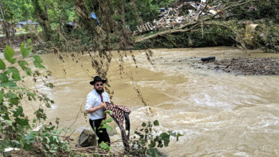 During a stop to deliver an aid package and a word of comfort, Rabbi Shlomo Litvin helped clear debris from the river bordering a home damaged in the flood. Credit: Courtesy of Chabad of Kentucky.