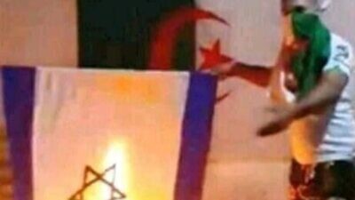 Mohamed Baha Dridi posted a video of himself in 2019 burning an Israeli flag with an Algerian flag in the background and covering his face, according to posts uncovered by the French Jewish Defense League. Source: Screenshot.