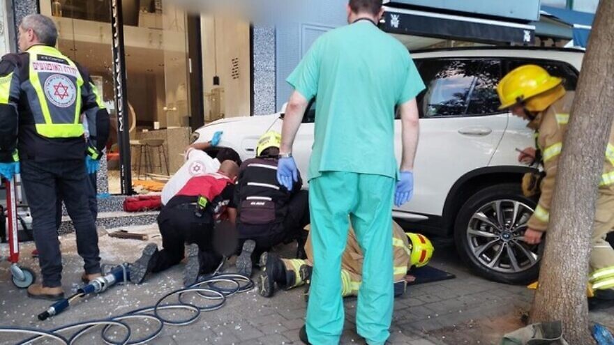Israeli firefighters and Magen David Adom medics help rescue and treat people trapped under a car that hit four pedestrians in Credit: MDA.