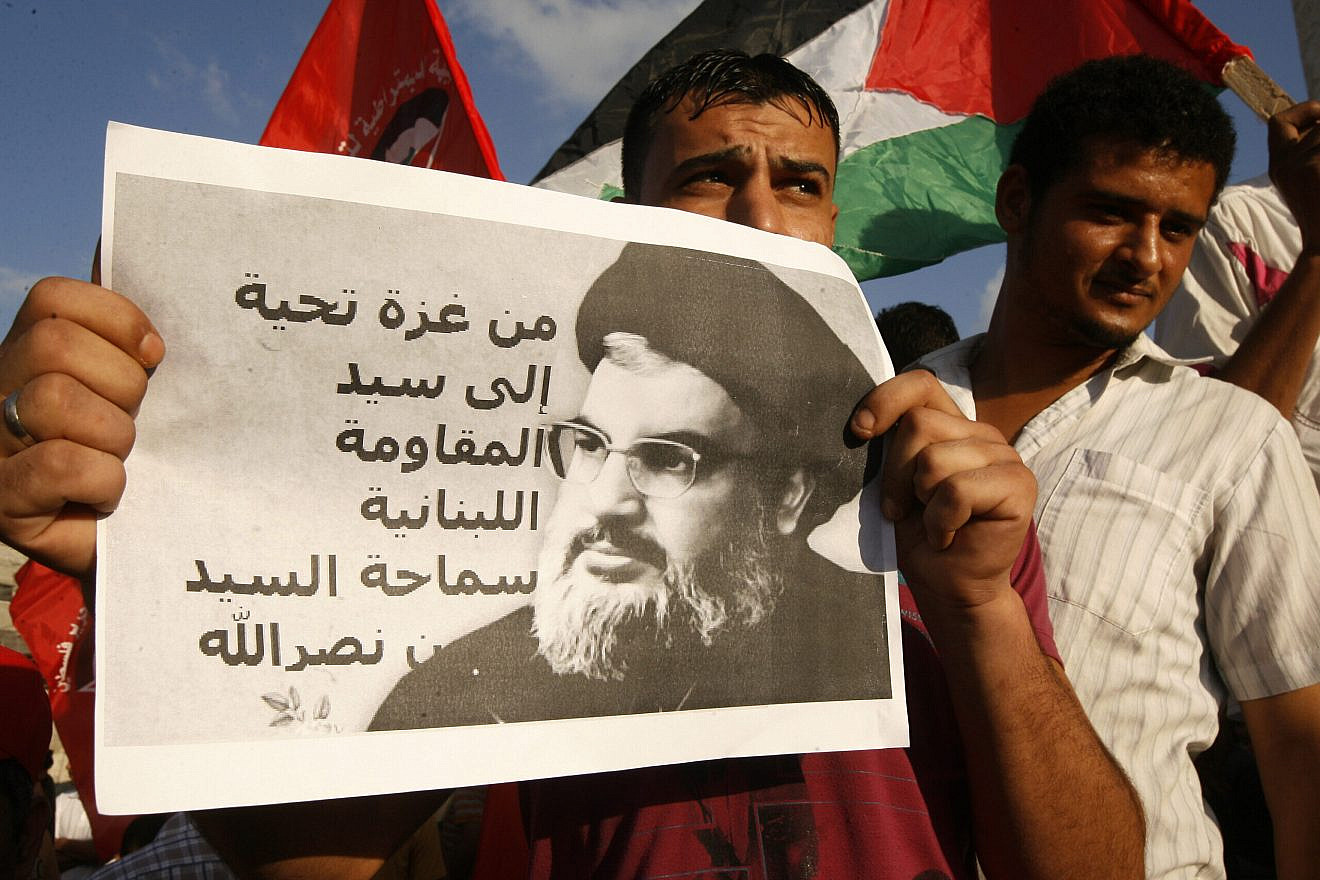 A Palestinian protester from the Popular Front for the Liberation of Palestine (PFLP) holds a picture of Hassan Nasrallah, the head of Lebanon’s militant Shi’ite Muslim movement Hezbollah, with a slogan that reads in Arabic “Regards from Gaza to the leader of Lebanese resistance” during a demonstration in Rafah, in the Southern Gaza Strip, on Sept. 3, 2014, against U.S. and French military intervention in Syria. Photo by Abed Rahim Khatib/Flash90.