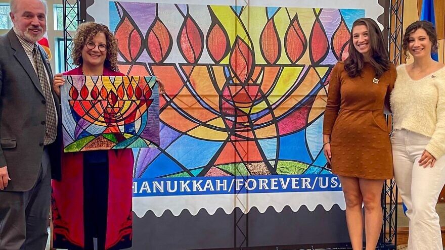 The “Hanukkah Forever” postage stamp is unveiled at Temple Emanu El in Orange Village, Ohio, on Oct. 20. Second from left is designer Jeanette Kuvin Oren. Credit: Courtesy Jeanette Kuvin Oren.