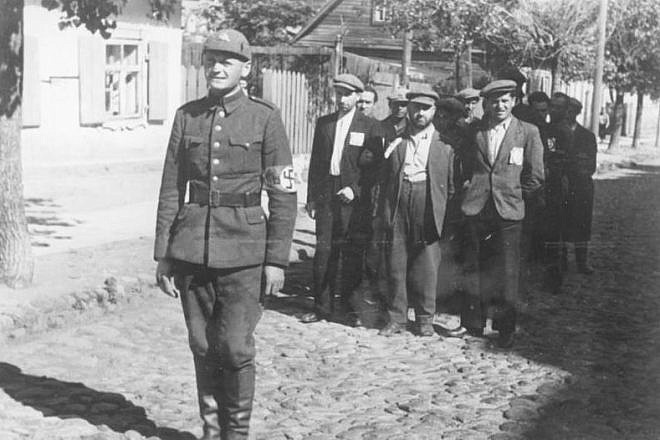 A Lithuanian policeman with Jewish prisoners, July 1941. Credit: Bundesarchiv/Wikimedia Commons.