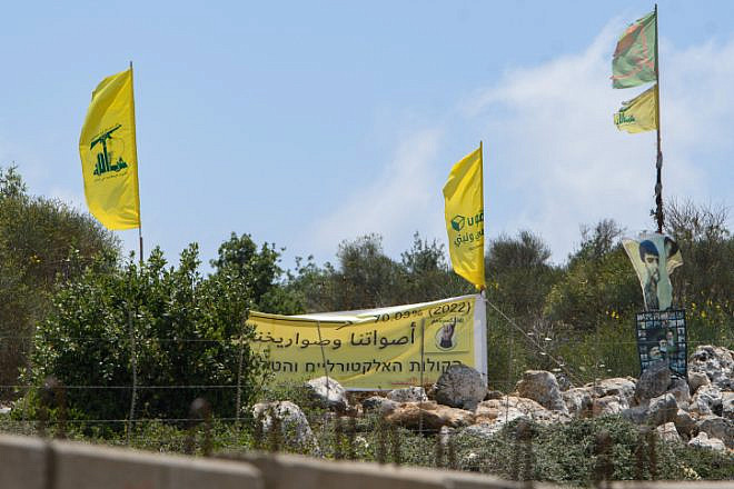 Hezbollah operatives in Lebanon raise the movement's banners at the Israeli border, July 3, 2022. Credit: Ayal Margolin/Flash90.