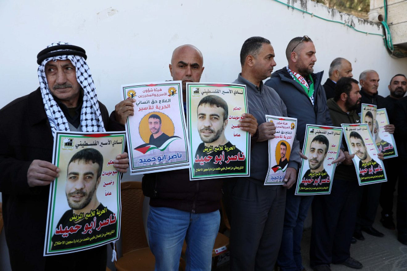 Palestinians hold pictures of terrorist Nasser Abu Hamid, then in Israeli prison, during a protest in Hebron demanding his release, Jan, 10, 2022. Photo by Wisam Hashlamoun/Flash90.