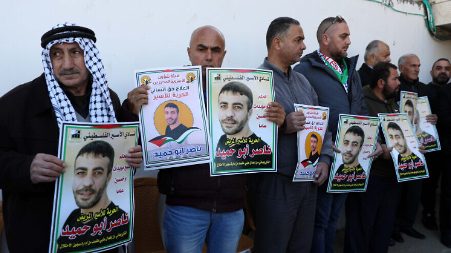 Palestinians hold pictures of terrorist Nasser Abu Hamid, then in Israeli prison, during a protest in Hebron demanding his release, Jan, 10, 2022. Photo by Wisam Hashlamoun/Flash90.