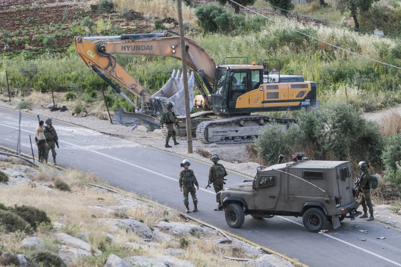 IDF soldiers stand guard as a bulldozer demolishes a Palestinian house that was built without a permit in the village of Beit Dajan, east of Nablus, May 9, 2022. Photo by Nasser Ishtayeh/Flash90.