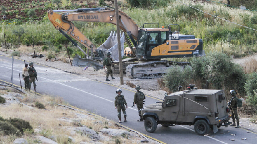 IDF soldiers stand guard as a bulldozer demolishes a Palestinian house that was built without a permit in the village of Beit Dajan, east of Nablus, May 9, 2022. Photo by Nasser Ishtayeh/Flash90.