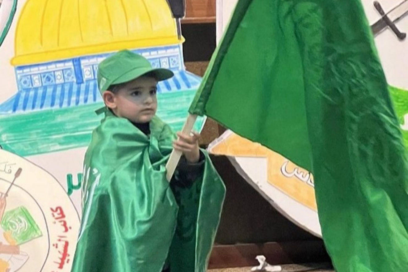 A boy holds a Hamas flag at the Al-Quds University event on Dec. 11, 2022. Source: T.me/kotlaalquds via MEMRI.