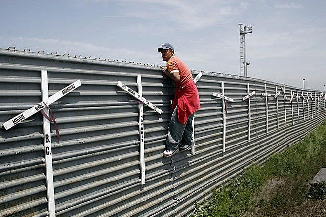 A migrant from Mexico scaling the border fence into the United States. Source: Wikimedia Commons.