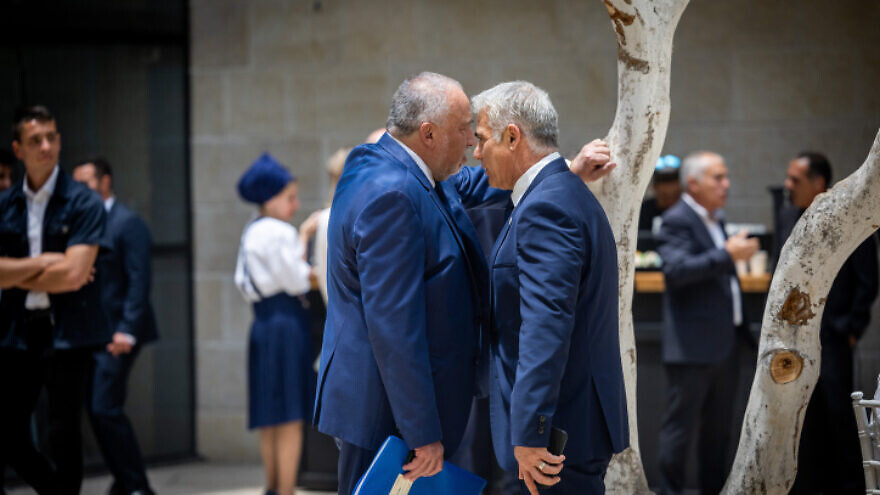 Now-former Finance Minister Avigdor Liberman and then-Foreign Minister Yair Lapid greet at a conference at the Givat Ram campus of the Hebrew University in Jerusalem, May 29, 2022. Photo by Yonatan Sindel/Flash90.