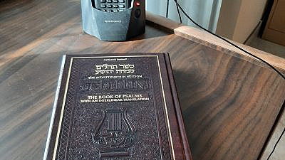 Flora Goldsmith’s setup for the OU tehillim and chizzuk calls includes a siddur and a headset