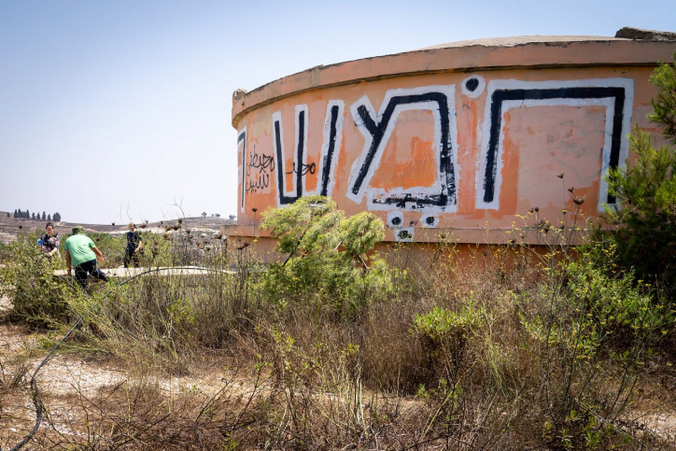Visitors walk by the water tower in the ruins of the former community of Homesh, Aug. 27, 2019. Photo by Hillel Maeir/Flash90.