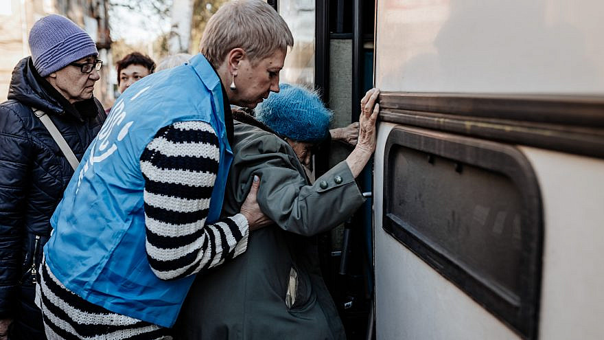 A JDC Jewish community volunteer helps an elderly woman onto a bus that is part of a JDC evacuation convo out of the city of Dnipro during the height of the conflict. Photo by Misha Kovalev.
