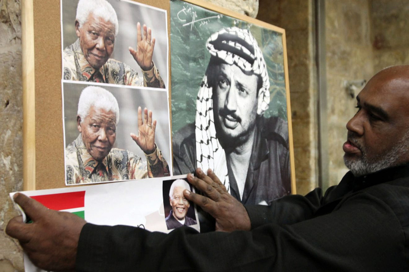 A Palestinian man hangs a picture of former South African leader Nelson Mandela next to a poster of former Palestinian chief Yasser Arafat, at a memorial service for Mandela in Jerusalem's Old City on Dec. 8, 2013. Photo by Sliman Khader/FLASH90.
