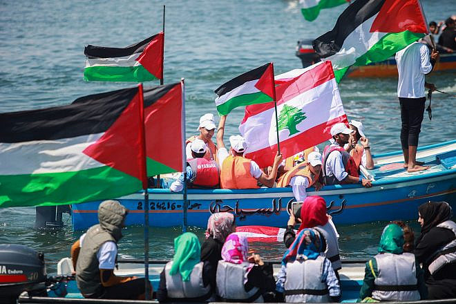 Palestinians hold flags as they ride a boat during a rally marking the 5th anniversary of the Mavi Marmara Gaza flotilla, at the seaport of Gaza City, May 31, 2015. Photo: Aaed Tayeh/Flash90