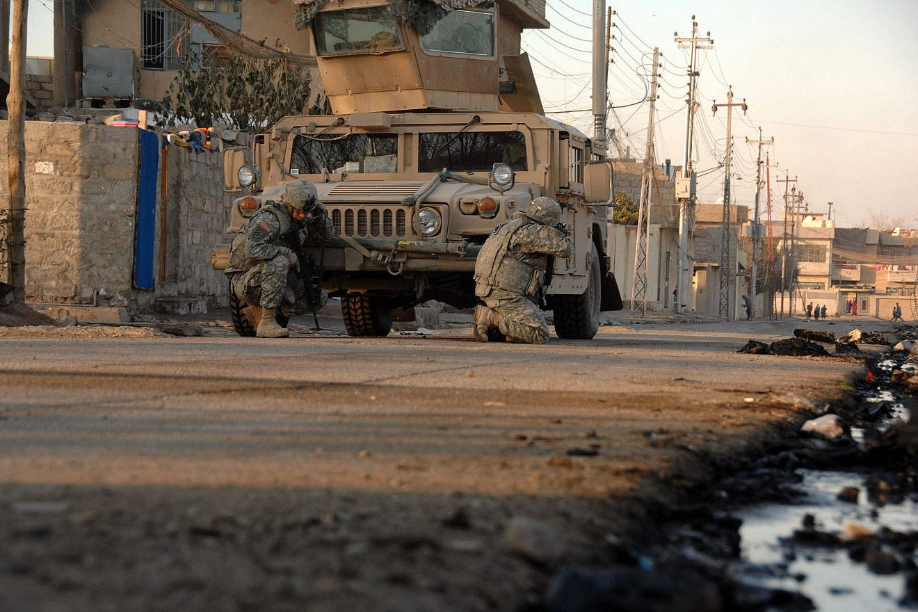 U.S. Army soldiers, attached to Heavy Company, 3rd Squadron, 3rd Armored Cavalry Regiment, take cover behind their vehicle as small-arms fire opens up in the distance in Mosul, Iraq, Jan. 17, 2008. Credit: Spc. Kieran Cuddihy/U.S. Army photo.