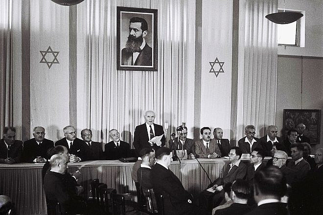 Israeli founding father and first prime minister David Ben-Gurion declares independence beneath a large portrait of Theodor Herzl, founder of modern Zionism, at the Tel Aviv Museum, today Independence Hall, on May 14, 1948. Photo by Zoltan Kluger/GPO.